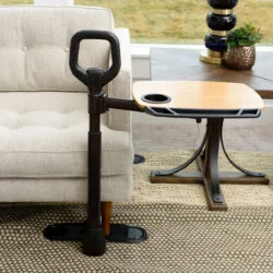 Sitting to standing aid with a dual pivoting tray next to a sofa.