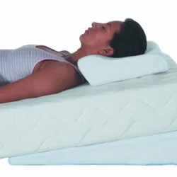 Person lying on an orthopaedic pillow and mattress tilter.