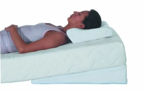 Person lying on an orthopaedic pillow and mattress tilter.