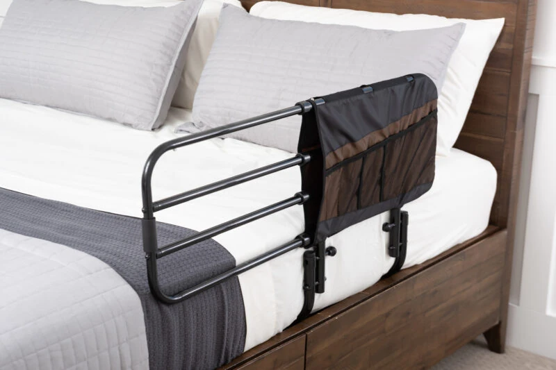 Bed rail with attached pouch on a wooden bed frame.