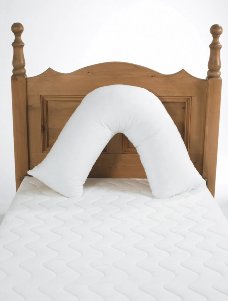 V shaped pillow on a wooden bed with white mattress.