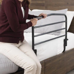 Person using a bed support rail attached to a wooden bed frame.