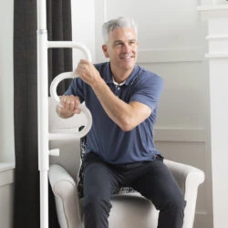 Man sitting and holding a white curved grab bar attached to a pole.