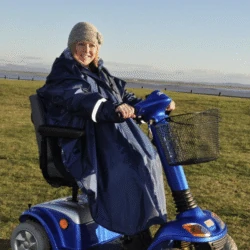 Person wearing a blue poncho on a mobility scooter outdoors.