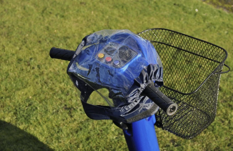 Mobility scooter control panel with a transparent cover outdoors.