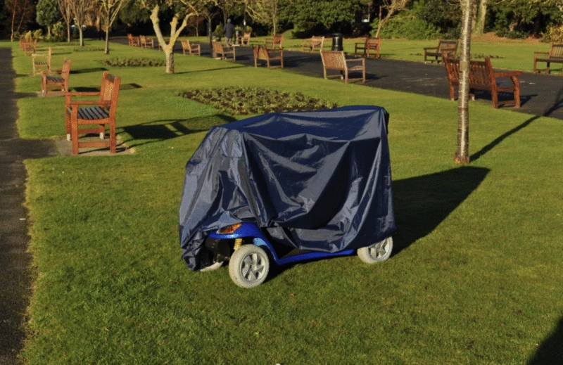 Navy rain cover on a mobility scooter in a park setting.