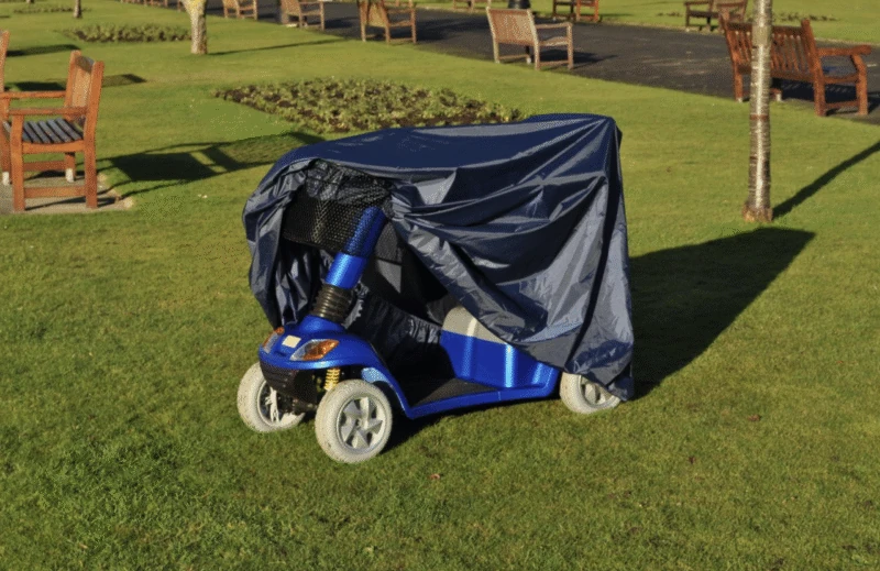 Blue mobility scooter with navy rain cover on grass