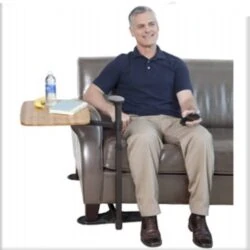 Man sitting on a sofa using a swivel table with a water bottle and book.
