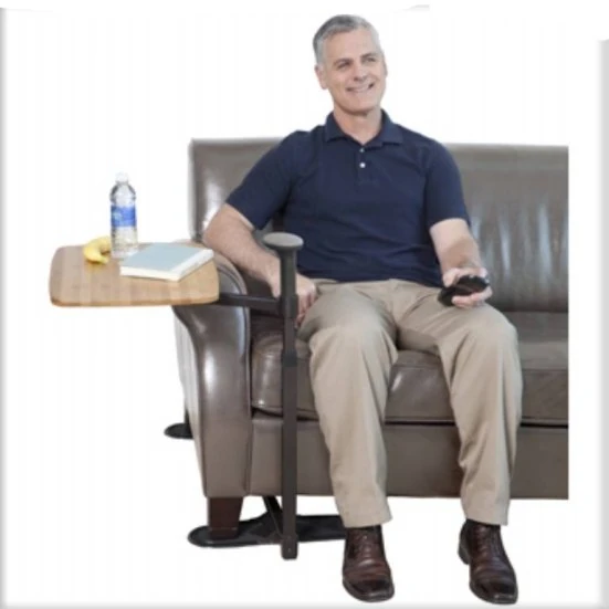 Man sitting on a sofa using a swivel table with a water bottle and book.