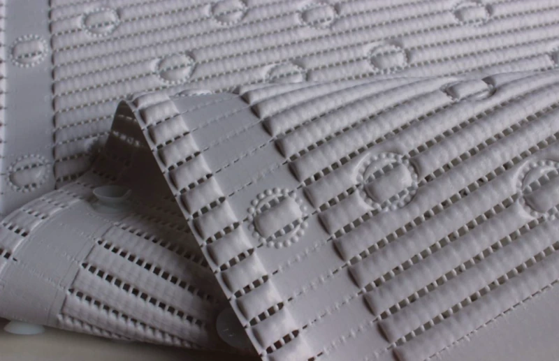 Close-up of white anti-slip bath mat with textured circles and lines.