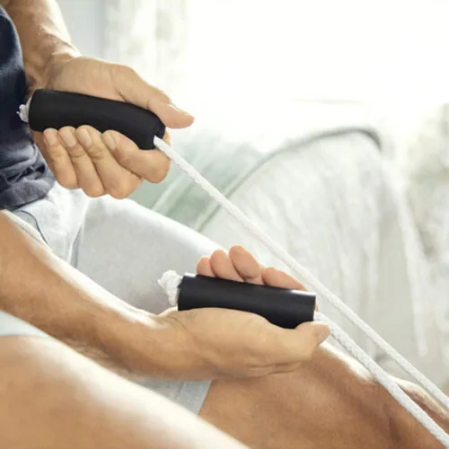 Person using a sock stocking aid with black handles and white rope.