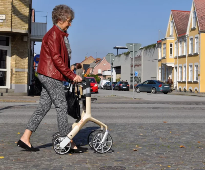 Elderly woman walking with a Let's Fly Rollator on a city street.