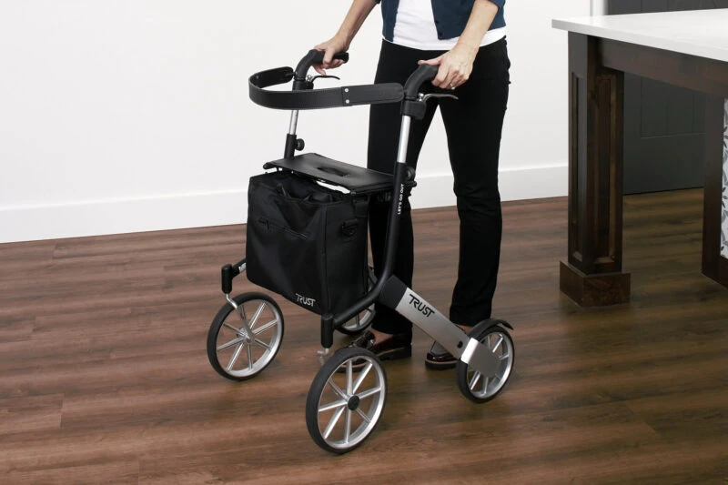Person using a Trust Rollator with large wheels indoors.