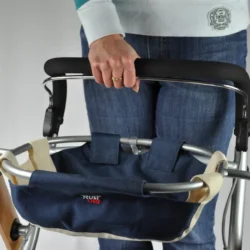 Person holding the handle of a Trust Care indoor rollator with a blue bag attached.