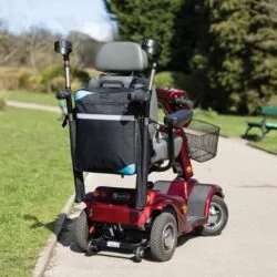 Mobility scooter with a black bag and crutch holder on a park path.
