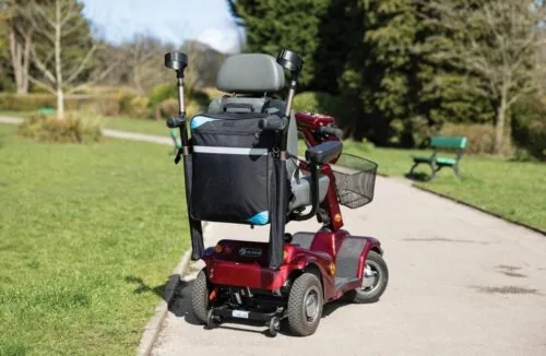 Mobility scooter with a black bag and crutch holder on a park path.