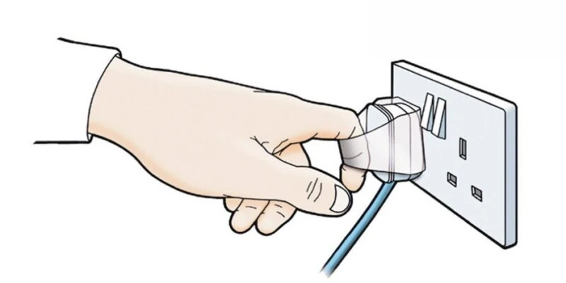 Hand using a Plug Tug to safely unplug a device from a wall socket.