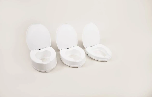 Three white elevated toilet seats with lids in different heights.