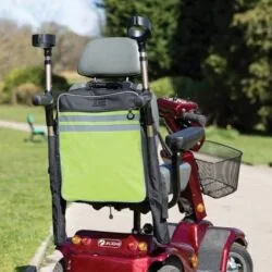 Mobility scooter with high visibility bag and crutch holder in a park.