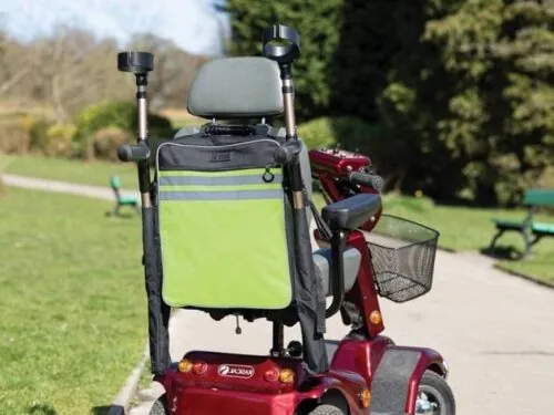 Mobility scooter with high visibility bag and crutch holder in a park.
