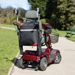 Mobility scooter with a black bag and crutch holder on a park path.