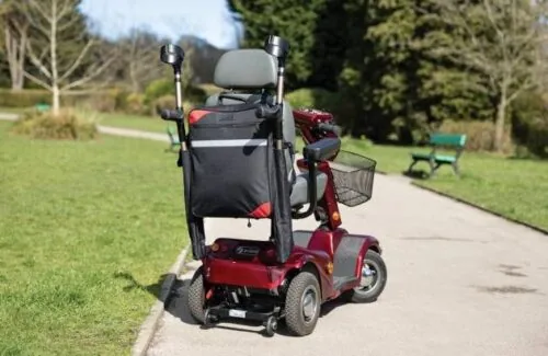Mobility scooter with a black bag and crutch holder on a park path.