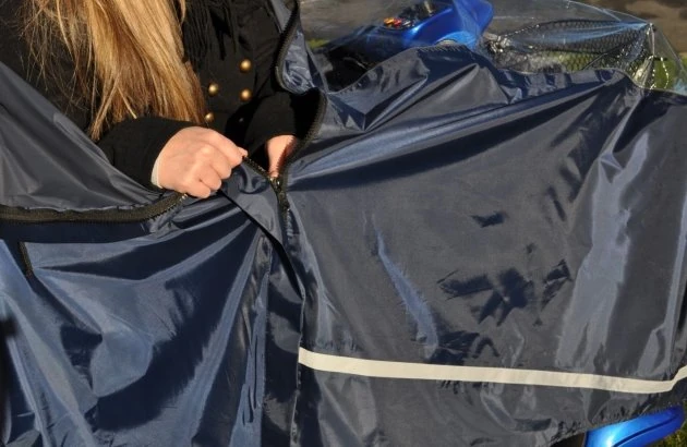 Person fastening a blue mobility scooter cape.