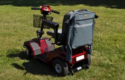 Mobility scooter with a grey bag attached to the back.