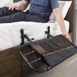 Person adjusting a bed rail with a pouch attached at the side of a bed.