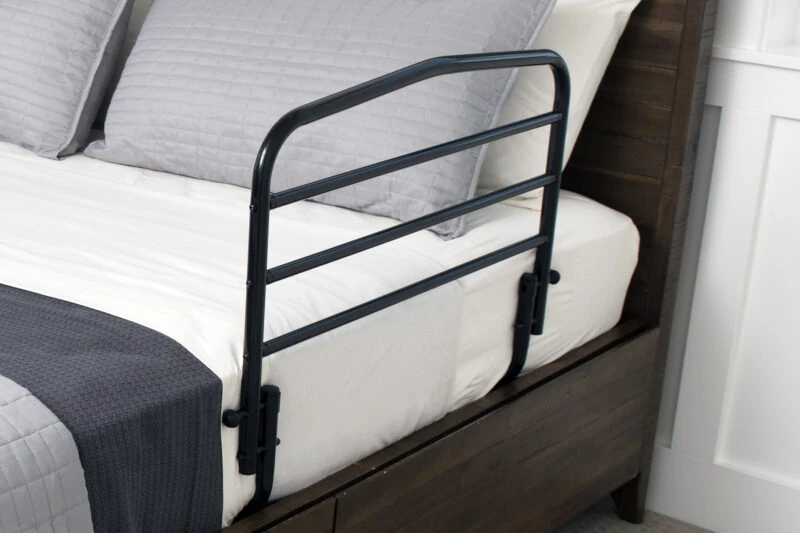 Black bed support rail attached to the side of a bed with gray bedding.
