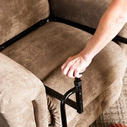 Person using a stand assist aid on a beige sofa.