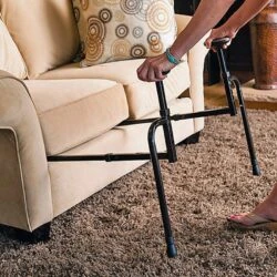 Person using a stand assist aid to rise from a sofa.