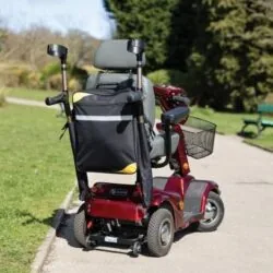 Mobility scooter with attached bag and crutch holder on a park path.