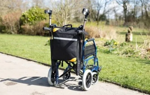 Mobility scooter bag with crutch holder attached to a wheelchair outdoors.