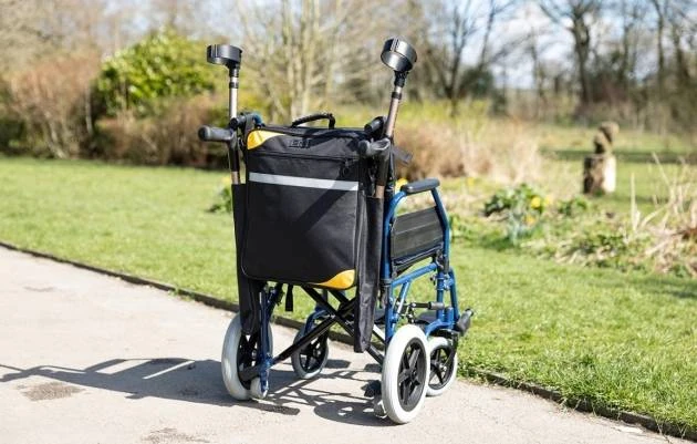 Mobility scooter bag with crutch holder attached to a wheelchair outdoors.