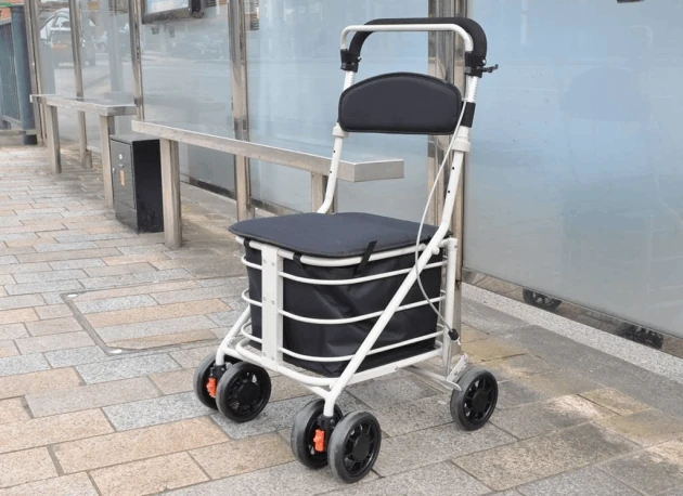 Shopping trolley with seat and four wheels on a sidewalk.