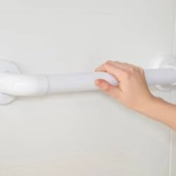Hand holding a white fluted grab rail mounted on a wall.