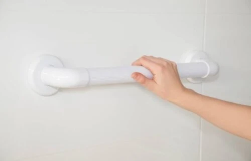 Hand holding a white fluted grab rail mounted on a wall.