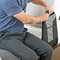 Man holding the handle of a Stander Bedside Econorail attached to a bed.