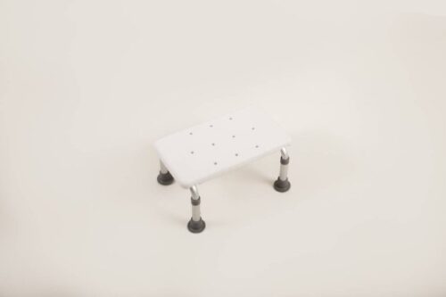 White bath step with adjustable legs and rubber feet.