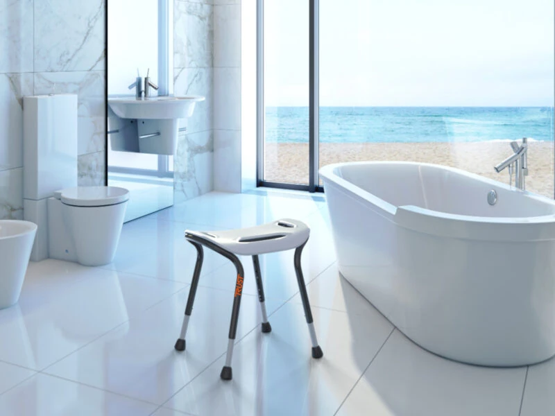 White bath stool with adjustable legs in a modern bathroom with a sea view.