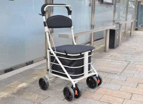 Black shopping trolley with seat and four wheels on a sidewalk.