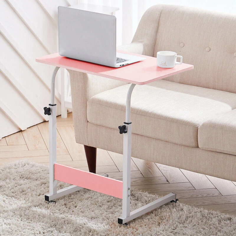 Pink over chair table with a laptop and mug beside a beige sofa.