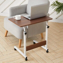 Over chair table with a laptop and mug on a wooden floor.