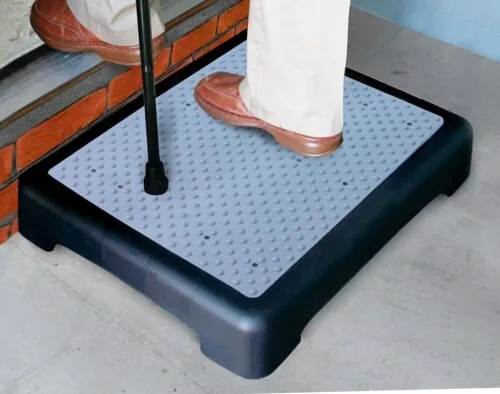 Person using a mobility step riser with a cane.