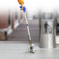 Person using a long reach grabber to pick up a can near a trash bin.