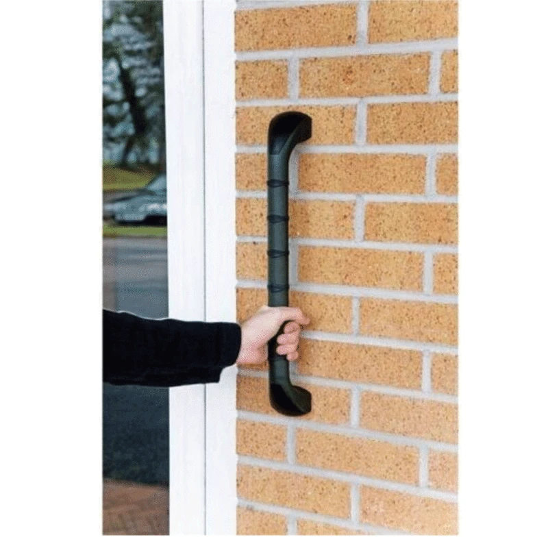 Hand holding a black safety handle mounted on a brick wall.
