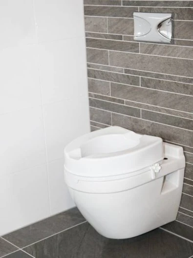 Raised toilet seat installed on a wall-mounted toilet in a modern bathroom.