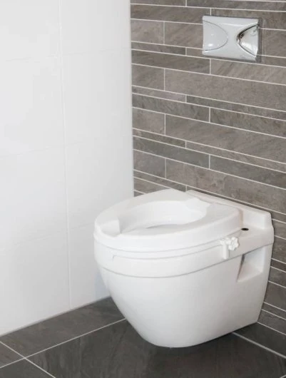 Raised toilet seat installed on a wall-mounted toilet in a modern bathroom.