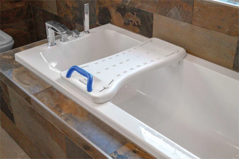 White bath board with blue handle placed over a bathtub.